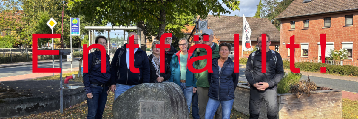 Eine Gruppe von Menschen stehen gemeinsam mit Bürgermeister Kai Eggert in Ingeln-Oessels vor einem großen Stein mit Gravur. Darüber der Schriftzug entfällt.