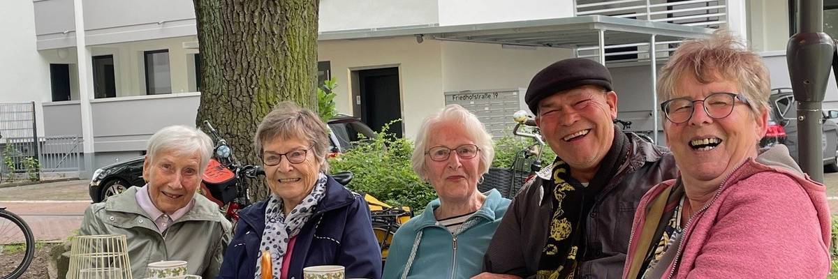 Eine Gruppe von Personen sitzen an einem Tisch im Park.