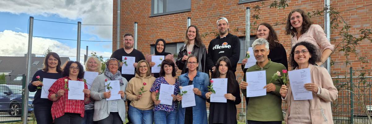 Die Teilnehmenden stehen im Halbkreis und zeigen ihre Teilnahmebescheinigung