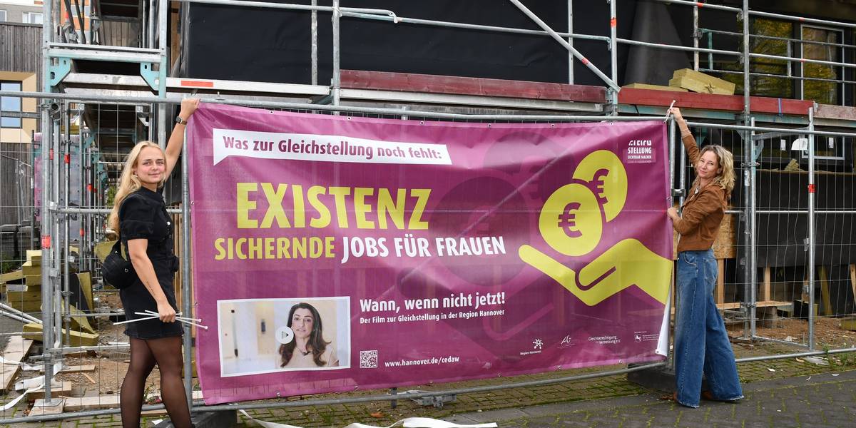 Mit Bannern wirbt die Kampagne um Aufmerksamkeit. © Stadt Laatzen / Anke Weisbrich Zwei Frauen bringen ein Banner an einem Baustellenzaun an.