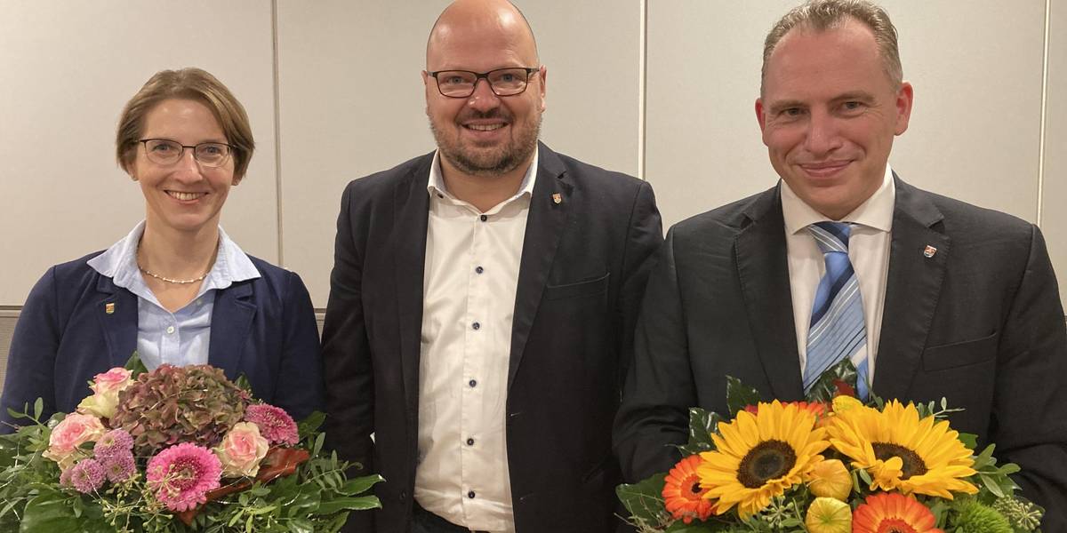 Der Bürgermeister überreicht seiner Vertreterin und dem zukünftigen Stadtrat jeweils Blumensträuße.