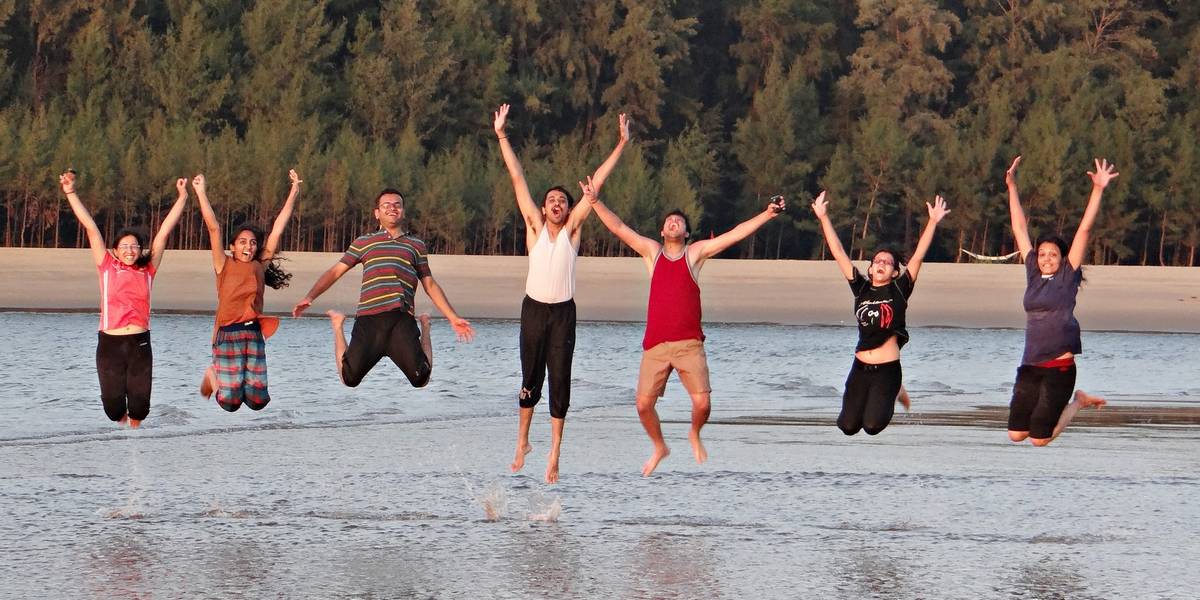 Eine Gruppe von Jugendlichen, die in einem Fluss in die Luft springen.