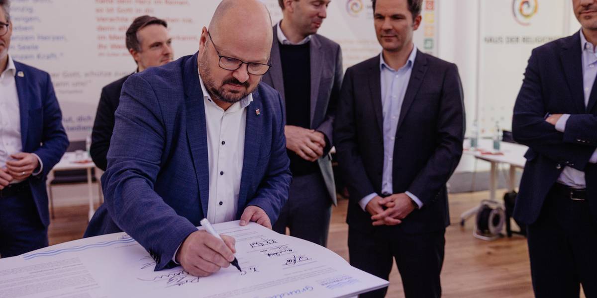 Ein Mann beugt sich über ein Dokument und unterschreibt dieses.