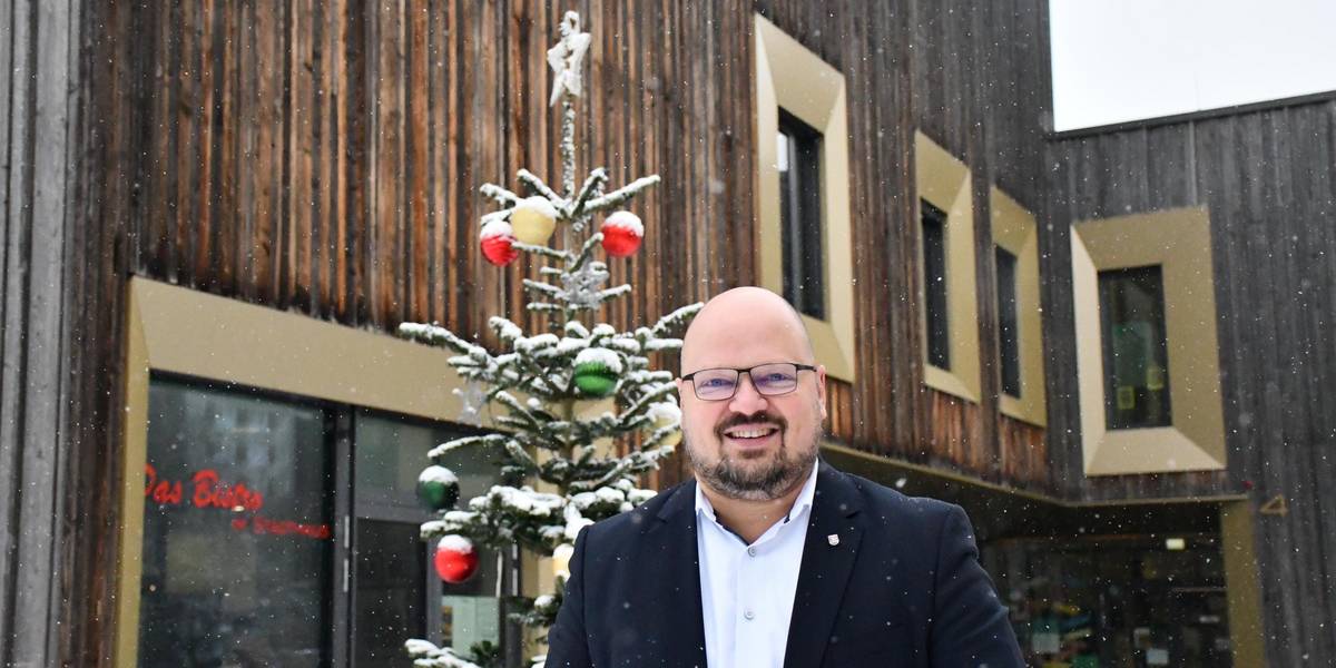 Bürgermeister Kai Eggert steht vor einem schneebedeckten Weihnachtsbaum