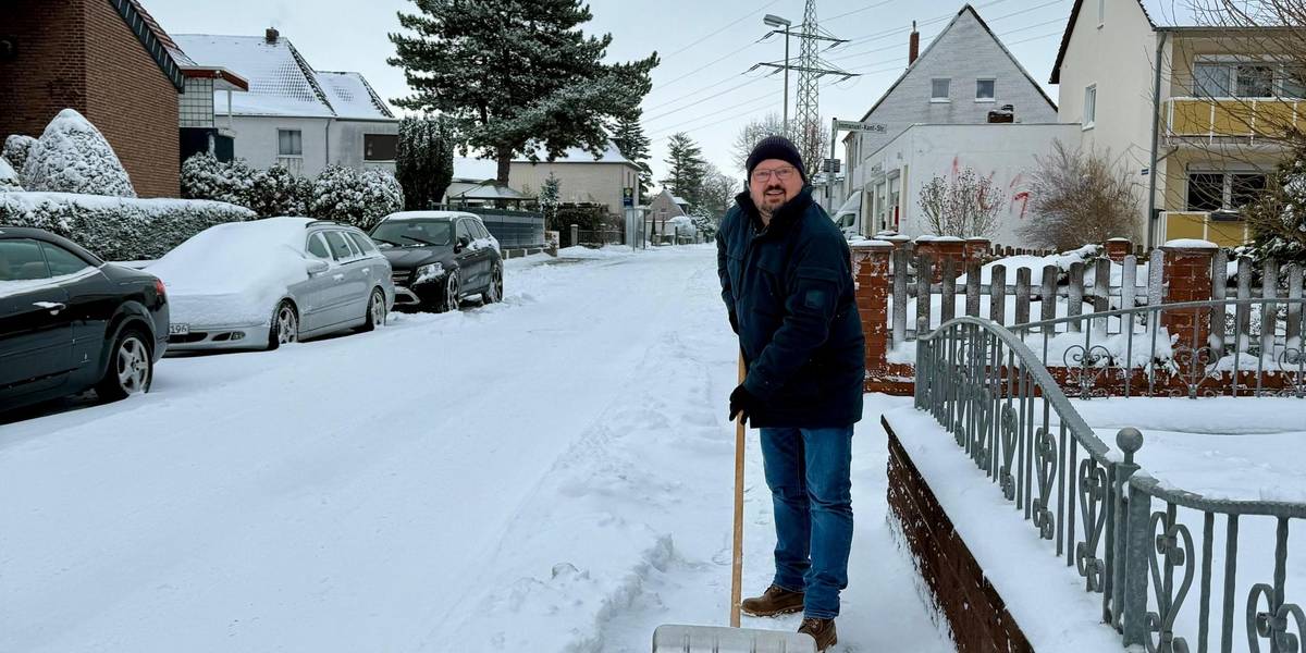 Bürgermeister Kai Eggert räumt mit dem Schneeschieber vor einem Grundstück.