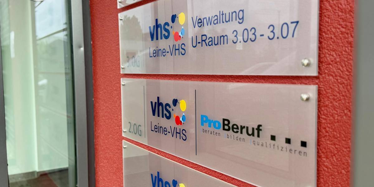 Eingang der Leine VHS © Stadt Laatzen Eine rote Wand mit Hinweisschildern der Leine VHS.