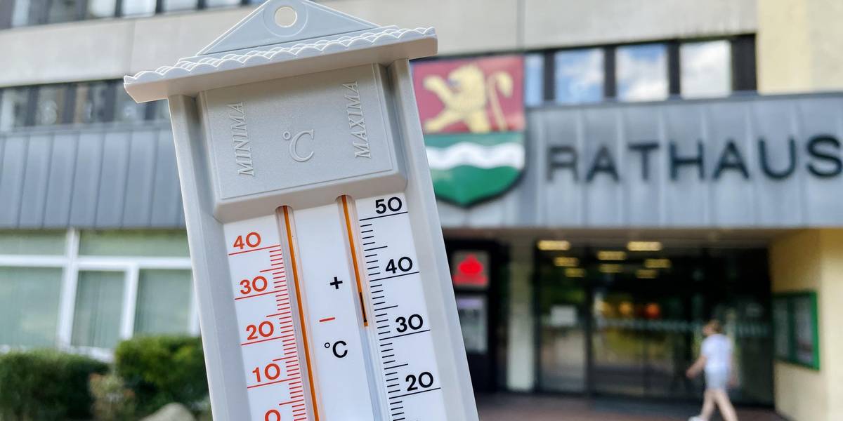 Der Deutsche Wetterdienst hat eine amtliche Hitzewarnung für die Region Hannover veröffentlicht © Stadt Laatzen Eine Hand hält ein analogen Thermometer; im Hintergrund sieht man das Rathaus