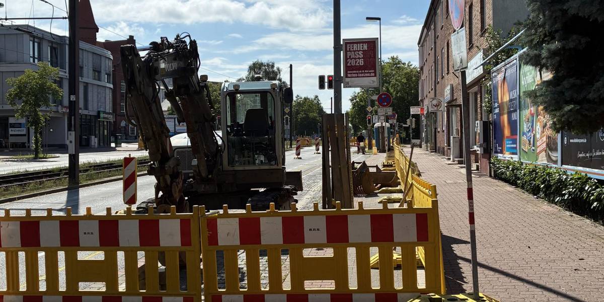 Gelbe Baustellenbaken sperren eine Baustelle ab, auf der bereits ein Bagger steht.