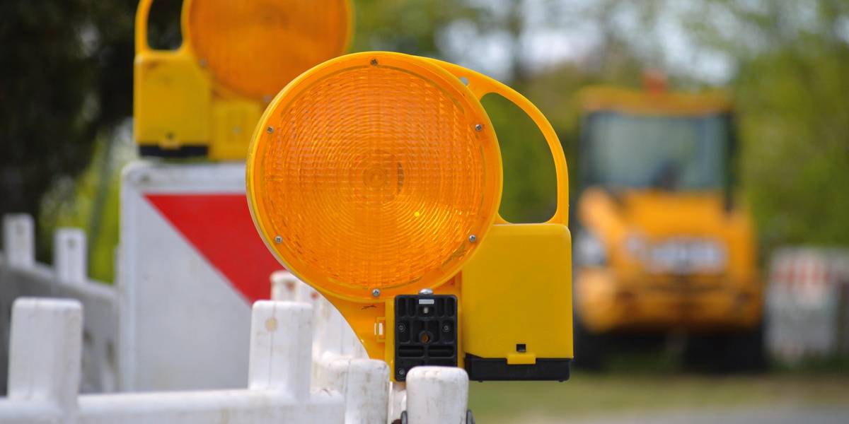 Symbolbild © Pixabay Straßenabsperrungen. Barken mit Signalleuchten. Im Hintergrund ist ein Bagger zu sehen.