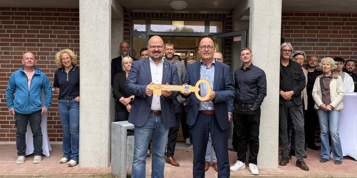 Zwei Männer stehen mit einem großen Schlüssel vor einem Haus.