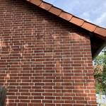 Eine rote Backsteinmauer ist mit Rissen durchzogen.