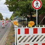 Baustellenbaken und Schilder kennzeichnen einen Behelfsgehweg.