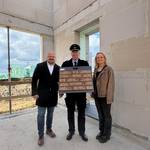 Drei Personen präsentieren eine Mustertafel mit einem roten Klinkerstein.