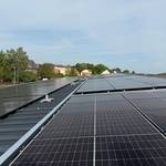 Dachfläche mit PV-Modulen vor einem leicht bewölkten Himmel