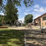 Die Außenanlage bietet Platz zum Spielen, Toben und Bewegen. Dazu gehören unter anderem Klettermöglichkeiten, eine Schaukel und naturnahe Aufenthaltsbereiche. © Stadt Laatzen Schulhof mit Bäumen und Spielgeräten