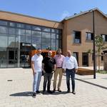 Laatzens Bürgermeister Kai Eggert (r.), Stadtrat Hauke Schröder (2. v. r.) stehen mit den Geschäftsführern und Architekten Murat Gazi Samut (l.) und Georgios Stavropoulos vom Planungsbüro ppb – Projektservice Planen und Bauen GmbH vor dem Haupteingang des neuen Grundschulbaus. In Planung, Bau und Einrichtung hat die Stadt Laatzen rund 16,07 Millionen Euro investiert. © Stadt Laatzen Vier Männer stehen vor einem sandfarbenen Klinkerneubau mit Glasfassade.