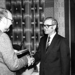 Oberkreisdirektor Herbert Droste gratuliert einem Herrn mit Anzug, Krawatte und Brille.