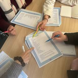 Die Teilnehmenden arbeiten an einem Arbeitsblatt. Sie sitzen in Kleingruppen am Tisch.