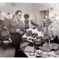 Menschen vor Tisch mit Kleidung Stoffen, möglicherweise ein Flohmarkt