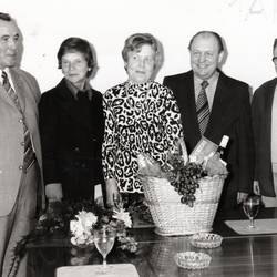 Geschenkekorb auf einem Tisch, dahinter 5 Personen, unter ihnen Alfred Thiemann und Erich Panitz