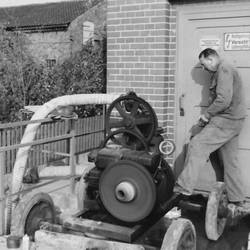 Arbeiter mit Arbeitsgerät, von dort führt Schlauch nach unten