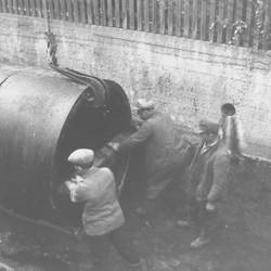 Drei Arbeiter sehen vor einem großen Rohr