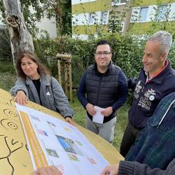 Frauen und Männer stehen an einem Spielgerät auf dem Spielplatz