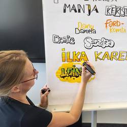 Dozentin sitzt an der Flipchart und führt eine Schriftart vor.