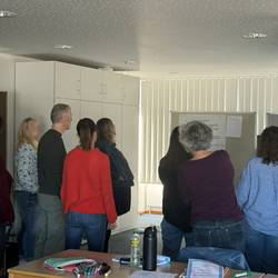 Die Teilnehmenden stehen mit der Referentin vor der Flipchart und besprechen den Leitgedanken.