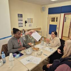 Die Teilnehmenden sitzen an einem Tisch und bearbeiten Arbeitsblätter.