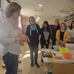 Die Referentin Frau Helms erklärt an einem Tisch den Arbeitsauftrag für die Teilnehmenden.