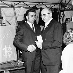 Zwei Herren schütteln sich in einem Festzelt die Hände, links ein Wimpel eines Gesangsvereins