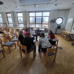 7 Teilnehmenden sitzen in einem Kreis und besprechen einen Kinderfall.