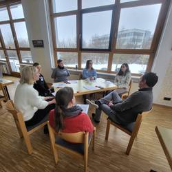 7 Teilnehmende sitzen in einem Kreis und besprechen einen Kinderfall.