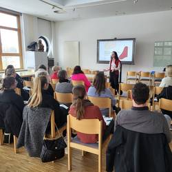 Frau Dr. Volf hält einen Vortrag. Die Teilnehmenden sitzen in der optimalen Kinositzordnung zur Referentin.