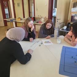 Es sitzen 4 Fachkräfte an einen Tisch und bearbeiten einen Fall.