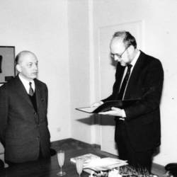 Oberkreisdirektor Herbert Droste mit einer Mappe in der Hand, daneben ein Herr mit Anzug und Krawatte.