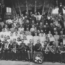 Gruppenfoto vor Gebäude, einige Menschen mit Instrumenten