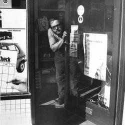 Mann öffnet Ladentür, an der Tür hängt ein Plakat mit Werbung für ein Feuerwehrfest