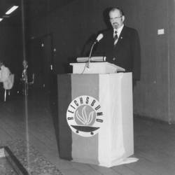 Mann vor Rednerpult mit Fahne von Reichsbund