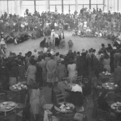 Veranstaltung mit vielen Menschen in Veranstaltungsaal mit gedeckten Tischen