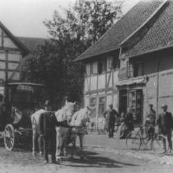 Kutscher mit Pferdekutsche und weitere Menschen vor Fachwerkhäusern