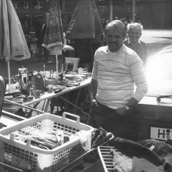 Zwei Herren an einem Verkaufsstand vermutlich bei einem Flohmarkt