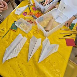 Auf dem Kreativtisch sieht am Knetutensilien und gebastelte Papierflieger.