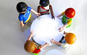 Mehrere Playmobilfiguren an einem runden Tisch stehend