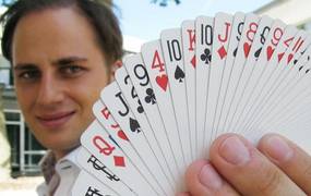 Mann hält Kartendeck vor seinem Gesicht