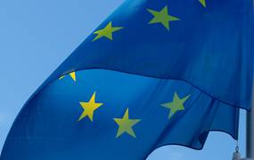 Die Flagge der EU weht im Wind vor einem blauen Himmel.