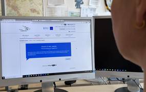 Eine Frau sitzt vor einem Bildschirm.