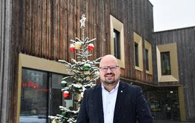Bürgermeister Kai Eggert steht vor einem schneebedeckten Weihnachtsbaum