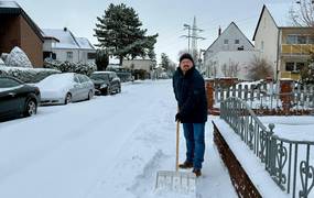 Bürgermeister Kai Eggert räumt mit dem Schneeschieber vor einem Grundstück.